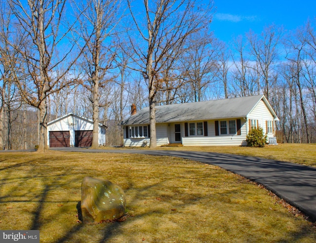 single story home with a front yard, a chimney, a detached garage, and an outbuilding