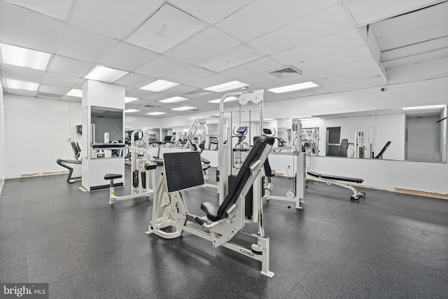 workout area with baseboards, visible vents, and a drop ceiling