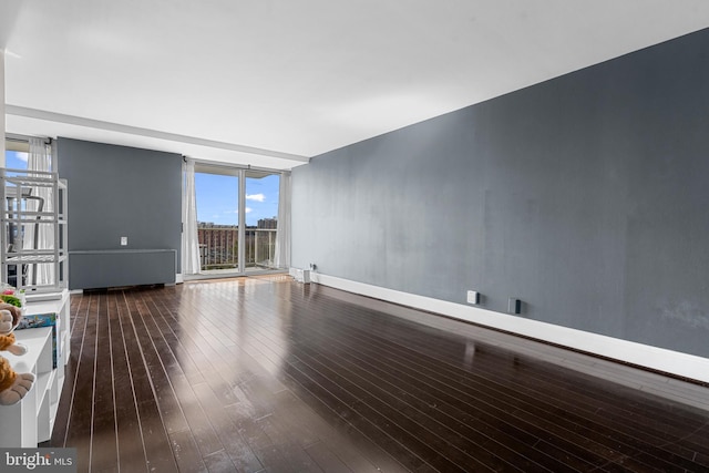 unfurnished living room featuring dark wood-style floors, baseboards, and floor to ceiling windows