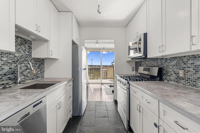 kitchen with appliances with stainless steel finishes, decorative backsplash, a sink, and white cabinets