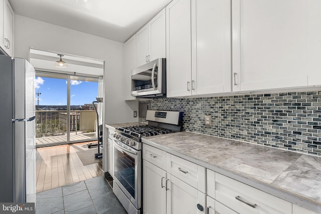 kitchen with stainless steel appliances, light countertops, backsplash, and white cabinetry