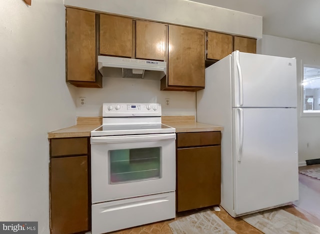 kitchen featuring brown cabinets, white appliances, under cabinet range hood, and light countertops