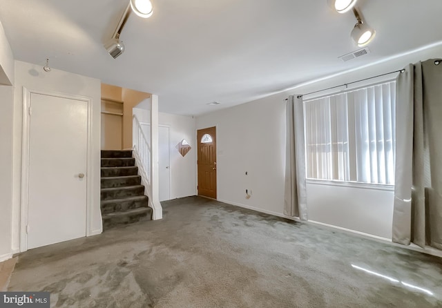 interior space featuring rail lighting, visible vents, stairway, and carpet