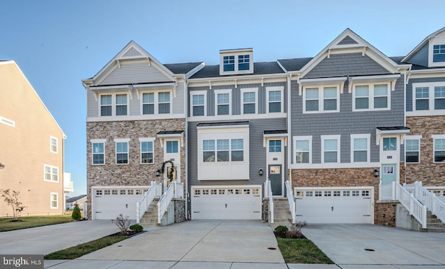 multi unit property featuring a garage, stone siding, and concrete driveway