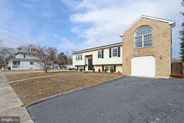 bi-level home with a garage, driveway, and brick siding