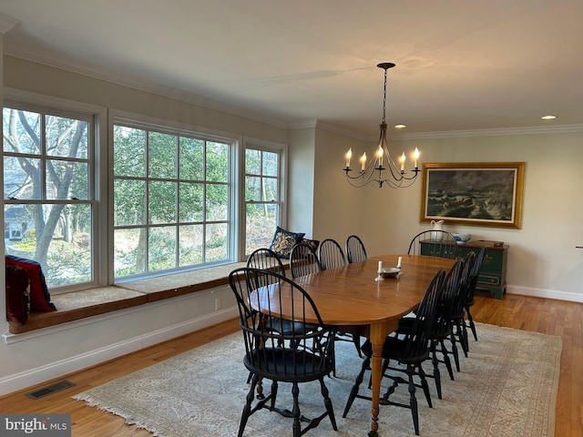 dining area with visible vents, crown molding, an inviting chandelier, and wood finished floors