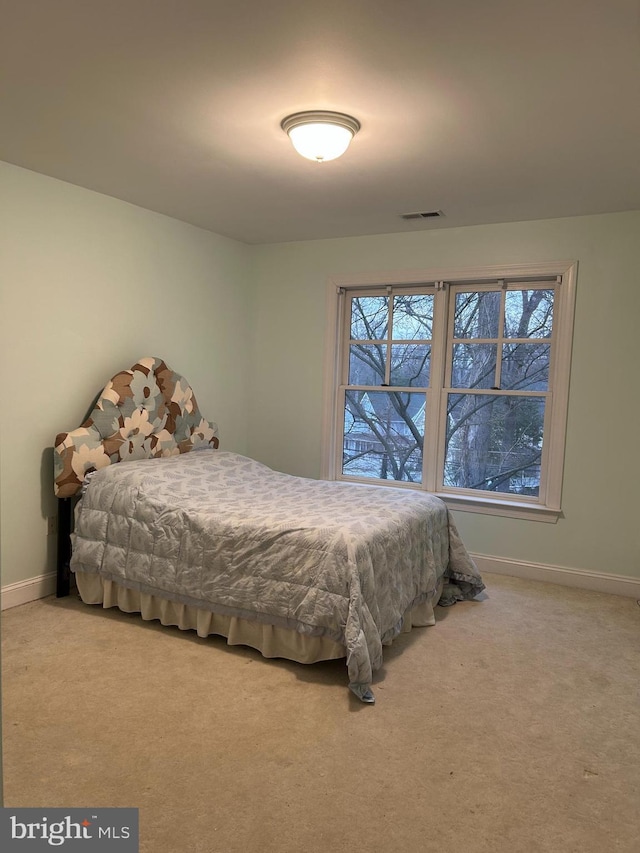 carpeted bedroom with visible vents, multiple windows, and baseboards