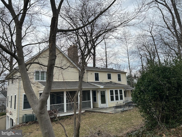 back of house featuring central air condition unit, a shingled roof, a chimney, and a patio area