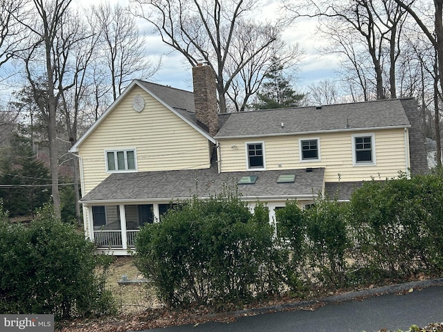 exterior space with a chimney and roof with shingles