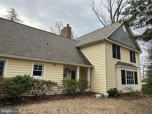 back of property featuring a chimney and a shingled roof