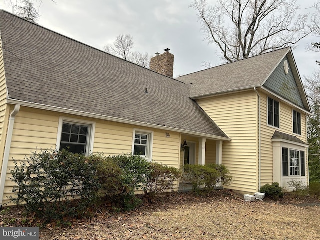 view of front of house with roof with shingles and a chimney