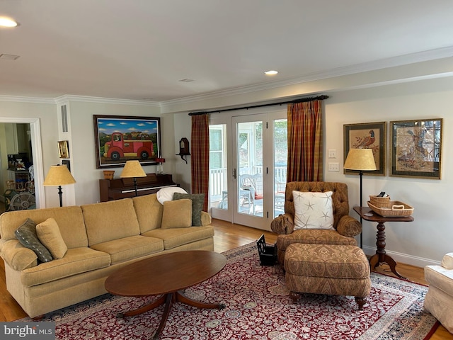 living area with crown molding, light wood-type flooring, and baseboards