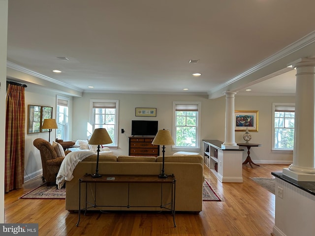 living area with a wealth of natural light, decorative columns, baseboards, and light wood-style floors