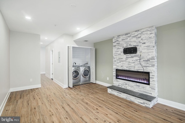 washroom with laundry area, a fireplace, wood finished floors, baseboards, and washer and clothes dryer