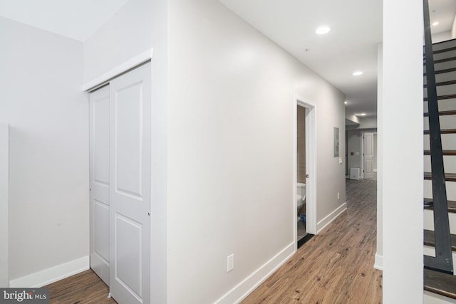 corridor featuring stairs, baseboards, wood finished floors, and recessed lighting