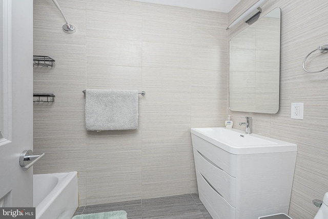 bathroom featuring walk in shower, tile walls, vanity, and a bathing tub