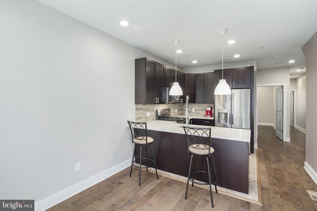 kitchen with a breakfast bar, wood finished floors, light countertops, range, and tasteful backsplash