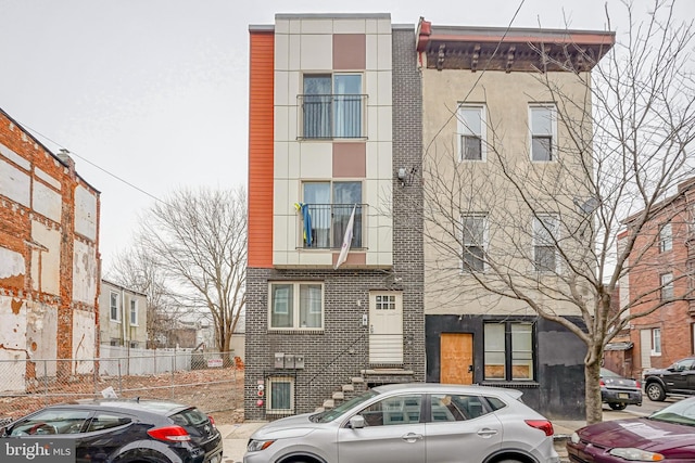 exterior space featuring brick siding, fence, and stucco siding