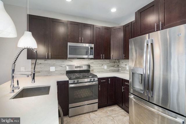 kitchen featuring tasteful backsplash, light countertops, appliances with stainless steel finishes, a sink, and dark brown cabinetry