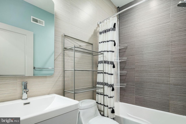 full bath with toilet, a sink, tile walls, visible vents, and shower / tub combo with curtain