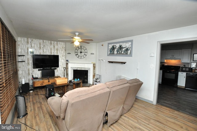 living area featuring ceiling fan, a fireplace, baseboards, and wood finished floors