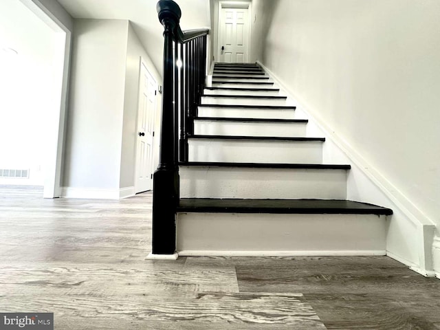 stairs with baseboards, visible vents, and wood finished floors