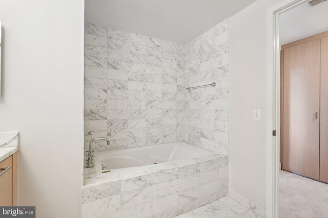 full bathroom with marble finish floor, tiled bath, visible vents, and vanity