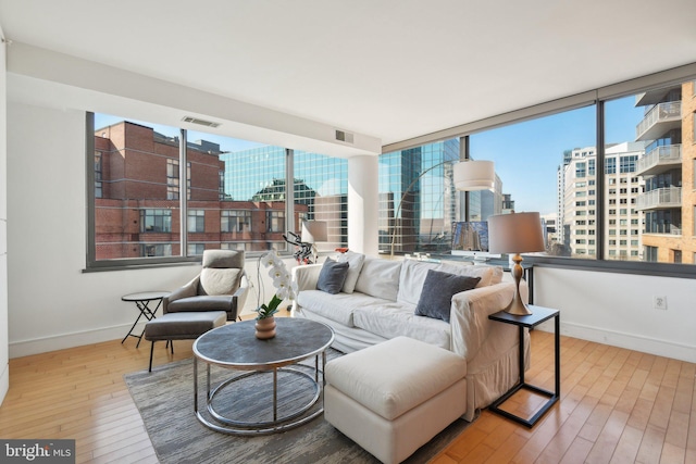 living room featuring a view of city, visible vents, hardwood / wood-style flooring, and a healthy amount of sunlight