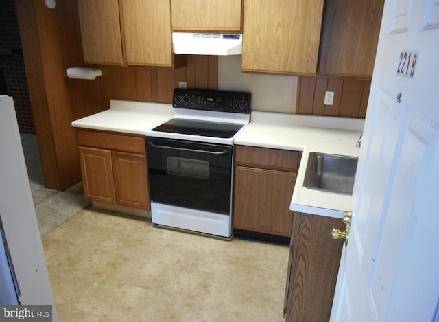 kitchen featuring electric range, brown cabinetry, ventilation hood, light countertops, and a sink