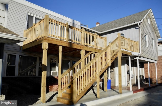 back of house with roof with shingles, a wooden deck, and stairs