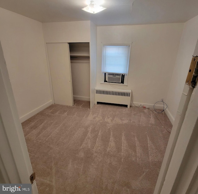 unfurnished bedroom featuring a closet, carpet flooring, baseboards, and radiator heating unit