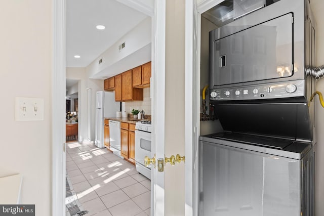 clothes washing area with light tile patterned floors, recessed lighting, visible vents, stacked washing maching and dryer, and laundry area