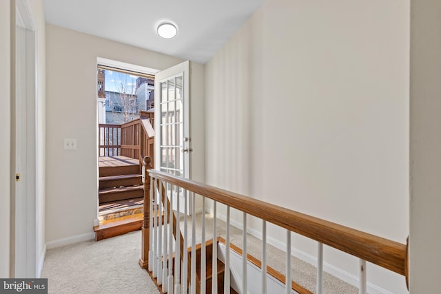 hall with an upstairs landing, carpet, and baseboards