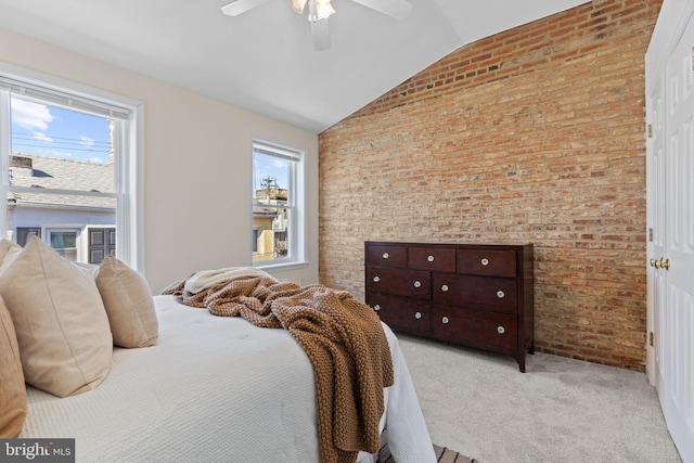 carpeted bedroom with vaulted ceiling, brick wall, multiple windows, and a ceiling fan