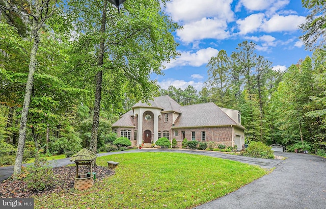 view of front of property featuring aphalt driveway, a garage, brick siding, and a front lawn