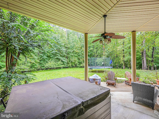 view of patio featuring a forest view, ceiling fan, and a trampoline