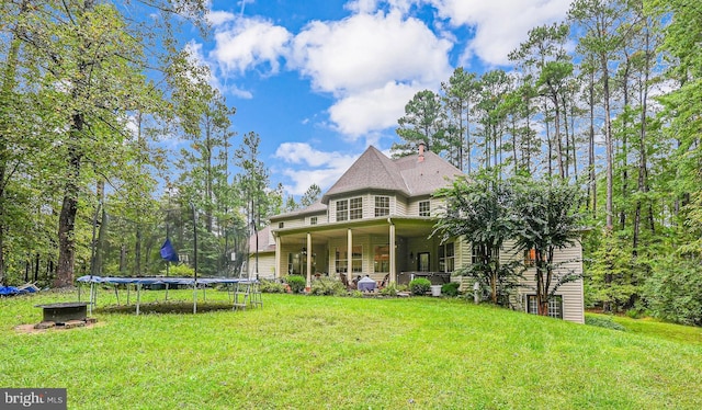 back of property with a trampoline and a lawn