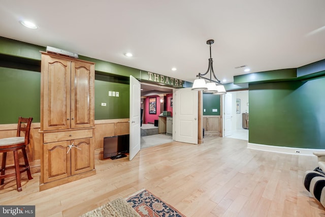 interior space featuring recessed lighting, light wood-style flooring, pendant lighting, and wainscoting