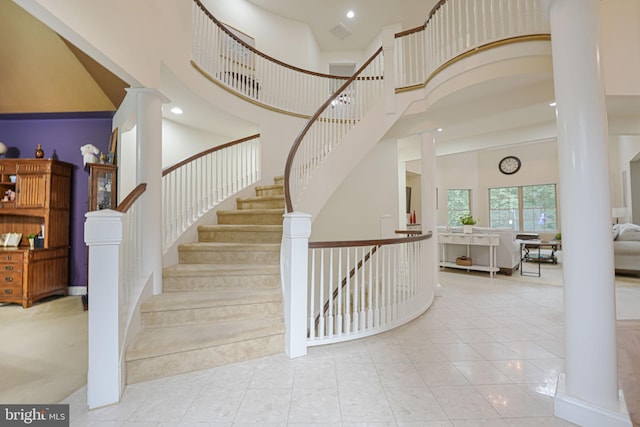 staircase featuring recessed lighting, decorative columns, a high ceiling, and tile patterned floors