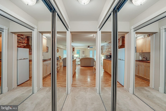 hall with light wood-type flooring and light colored carpet