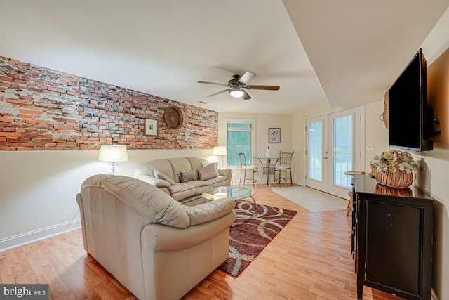 living room with a ceiling fan, light wood-type flooring, french doors, and baseboards