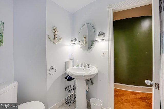 half bathroom featuring wood finished floors, toilet, and baseboards