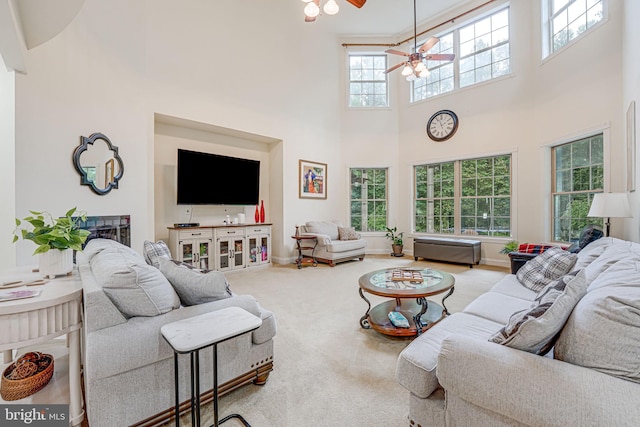 carpeted living room with a ceiling fan, a towering ceiling, and baseboards