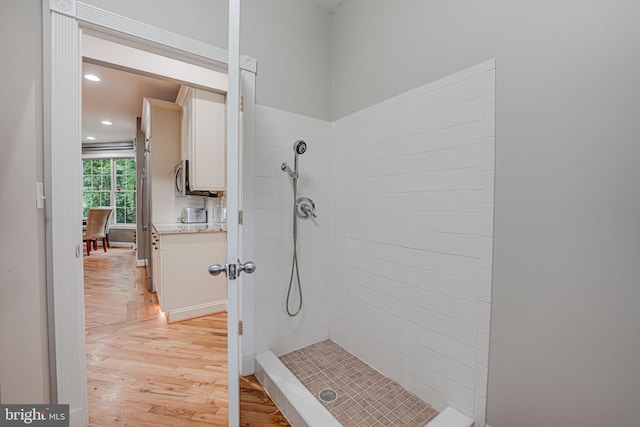 full bath featuring tiled shower, wood finished floors, and recessed lighting