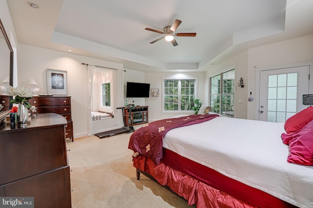 bedroom with baseboards, a ceiling fan, light colored carpet, access to exterior, and a tray ceiling