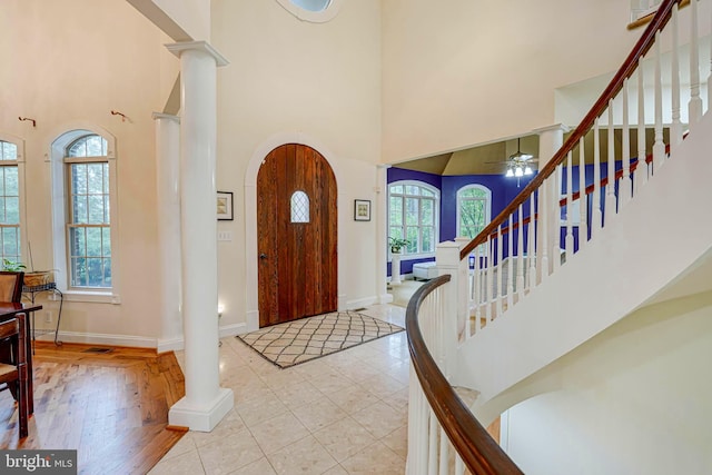 entrance foyer featuring a towering ceiling, ornate columns, stairs, and baseboards