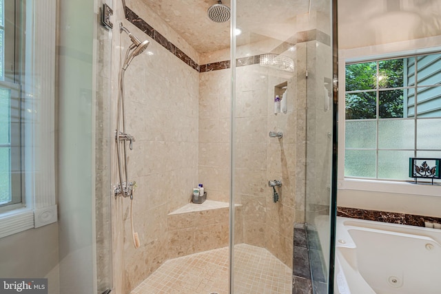 bathroom with a jetted tub, a shower stall, and a wealth of natural light