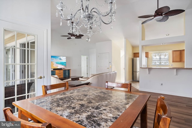 dining room featuring ceiling fan, a high ceiling, baseboards, and wood finished floors