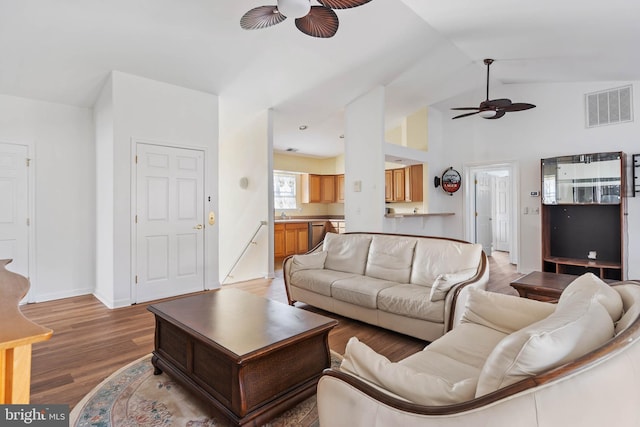 living room with visible vents, a ceiling fan, vaulted ceiling, wood finished floors, and baseboards