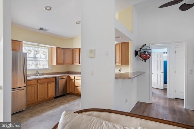 kitchen with ceiling fan, stainless steel appliances, a high ceiling, a sink, and visible vents